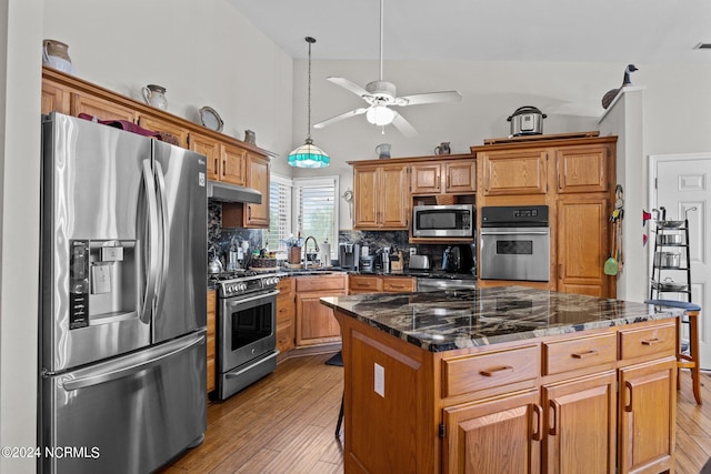 kitchen with sink, appliances with stainless steel finishes, light hardwood / wood-style flooring, and a kitchen island