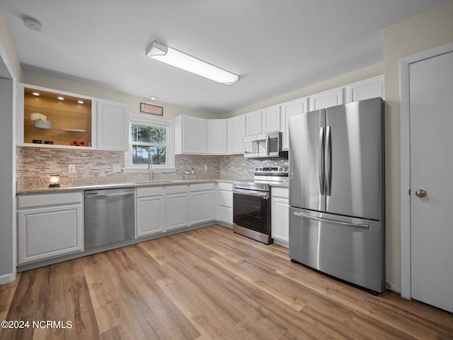 kitchen with stainless steel appliances, backsplash, and light wood-type flooring