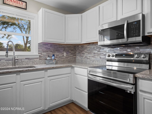 kitchen with stainless steel appliances, sink, white cabinetry, and dark hardwood / wood-style floors