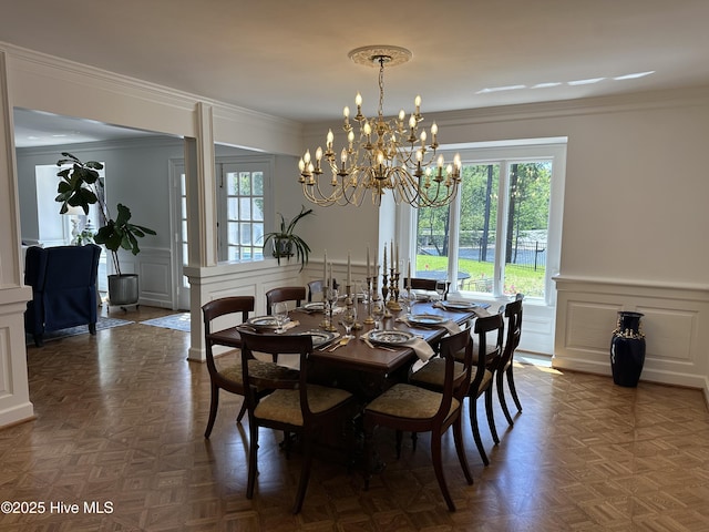 dining area featuring a decorative wall, crown molding, wainscoting, and a healthy amount of sunlight