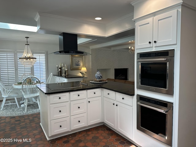 kitchen with a peninsula, dark countertops, a chandelier, and extractor fan