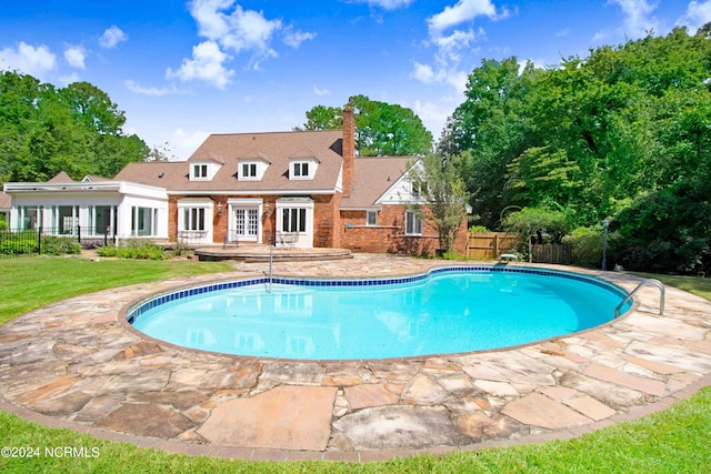 view of pool with a diving board, a yard, and a patio