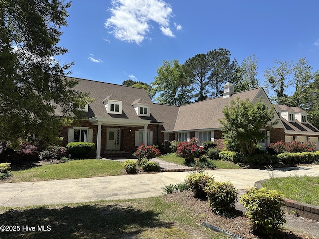 cape cod home with a front lawn, brick siding, and roof with shingles