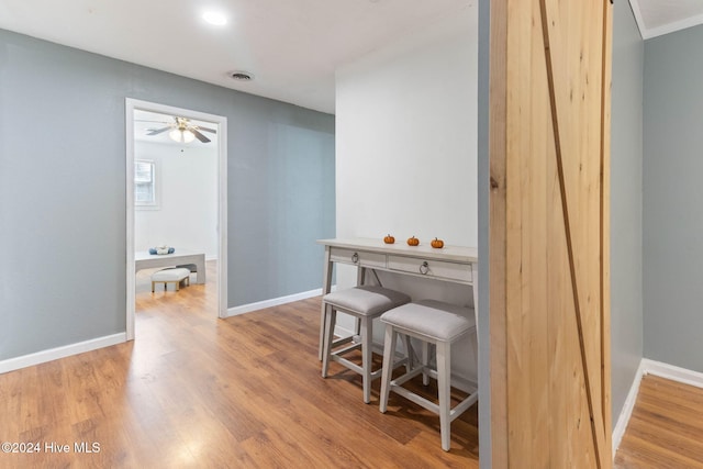 dining area featuring light wood-type flooring, ceiling fan, and a barn door