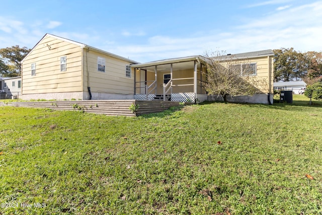 rear view of property with a sunroom and a yard