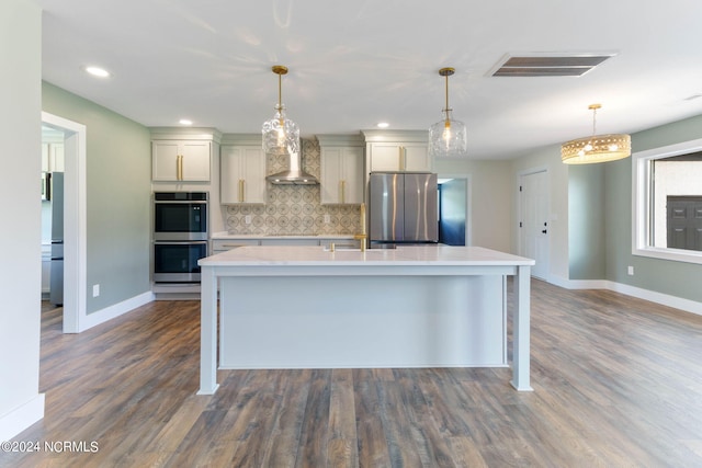 kitchen featuring dark hardwood / wood-style flooring, tasteful backsplash, stainless steel appliances, wall chimney range hood, and decorative light fixtures