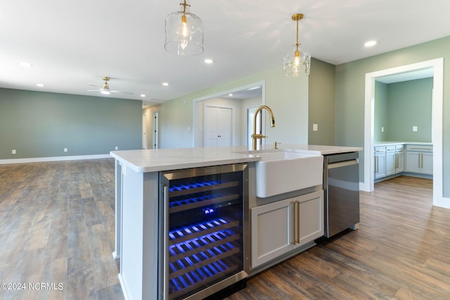 kitchen with an island with sink, decorative light fixtures, beverage cooler, and sink