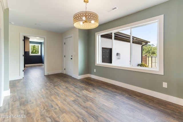 unfurnished room featuring dark hardwood / wood-style floors and an inviting chandelier