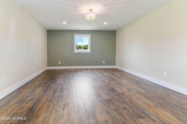 spare room with dark hardwood / wood-style flooring and an inviting chandelier