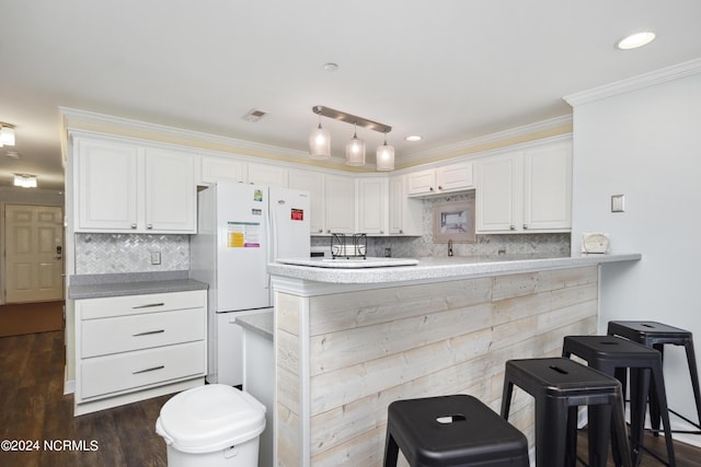 kitchen featuring dark hardwood / wood-style flooring, white refrigerator, decorative backsplash, white cabinets, and ornamental molding