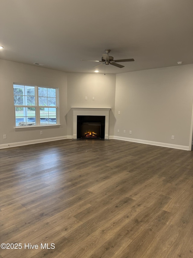 unfurnished living room featuring dark wood-type flooring and ceiling fan