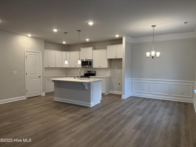 kitchen featuring an island with sink, stainless steel appliances, decorative light fixtures, dark hardwood / wood-style flooring, and white cabinets