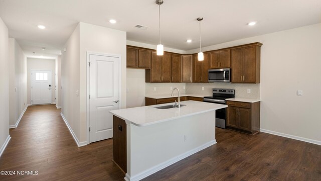 kitchen featuring dark wood-type flooring, stainless steel appliances, sink, and an island with sink