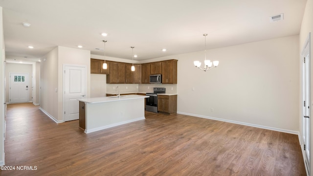 kitchen with hardwood / wood-style floors, a kitchen island with sink, stainless steel appliances, and hanging light fixtures