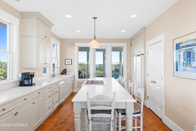 kitchen featuring a kitchen bar, sink, pendant lighting, light hardwood / wood-style flooring, and white fridge with ice dispenser