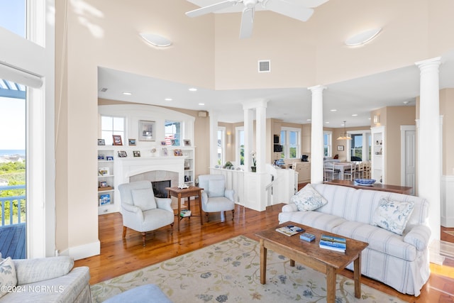 living room with a fireplace, a high ceiling, ceiling fan, and hardwood / wood-style floors