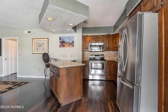 kitchen featuring a textured ceiling, a kitchen island, stainless steel appliances, and tasteful backsplash