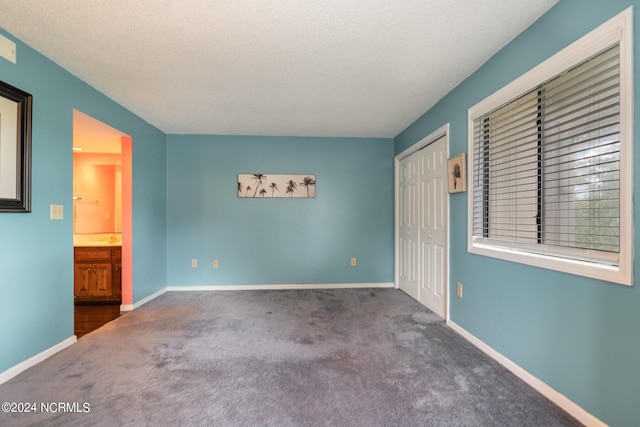 empty room featuring dark colored carpet and a textured ceiling