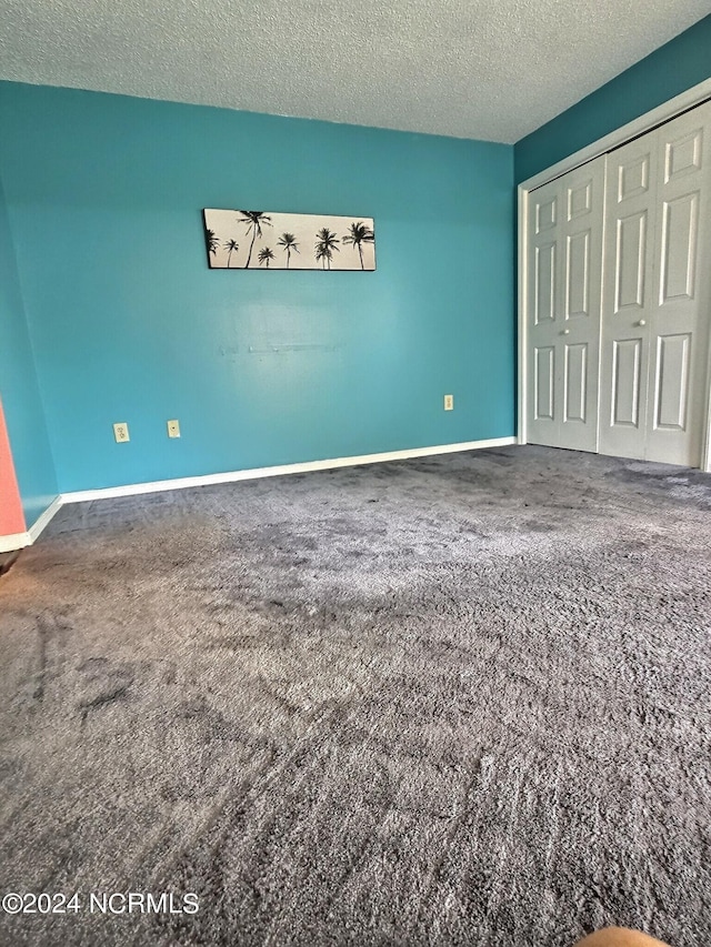 unfurnished bedroom with a textured ceiling, carpet floors, and a closet