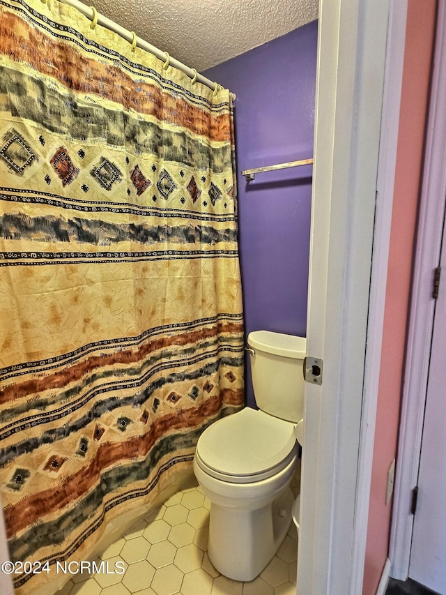 bathroom with tile patterned flooring, a textured ceiling, and toilet