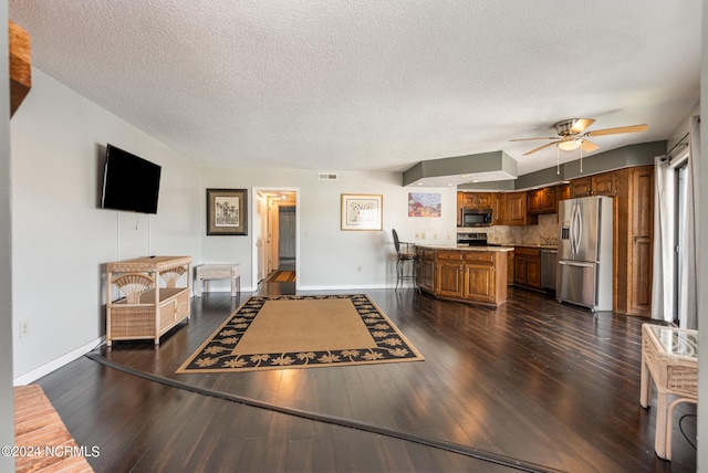 living room featuring ceiling fan, dark hardwood / wood-style flooring, and a textured ceiling