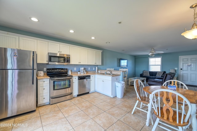 kitchen with white cabinets, a peninsula, stainless steel appliances, light countertops, and light tile patterned flooring