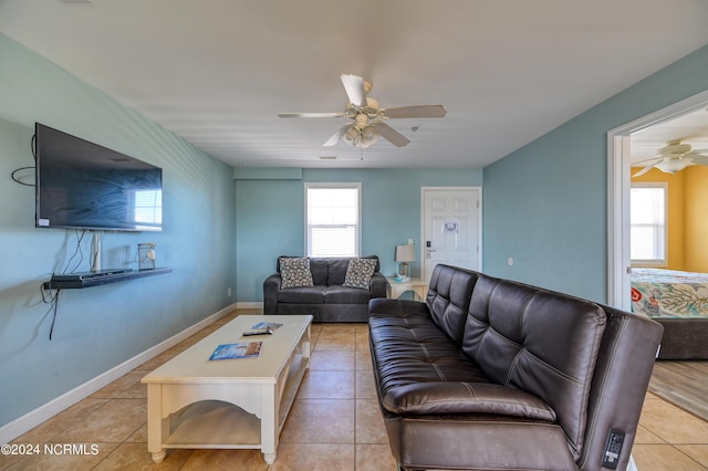 living area featuring a ceiling fan, baseboards, and light tile patterned floors