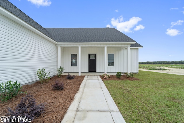 doorway to property featuring a porch and a lawn