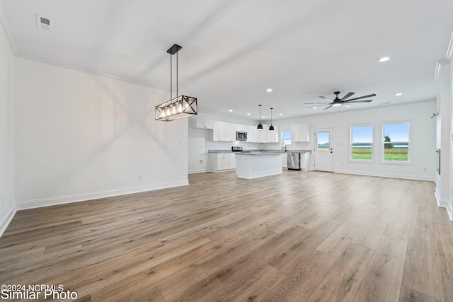 unfurnished living room with ornamental molding, light hardwood / wood-style floors, ceiling fan, and sink