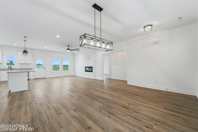 unfurnished living room with ceiling fan, sink, and hardwood / wood-style floors