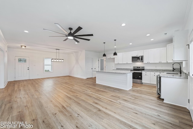 kitchen featuring appliances with stainless steel finishes, light hardwood / wood-style floors, white cabinetry, a kitchen island, and ceiling fan