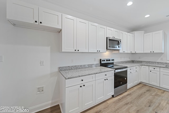 kitchen featuring light stone counters, white cabinets, ornamental molding, stainless steel appliances, and light wood-type flooring