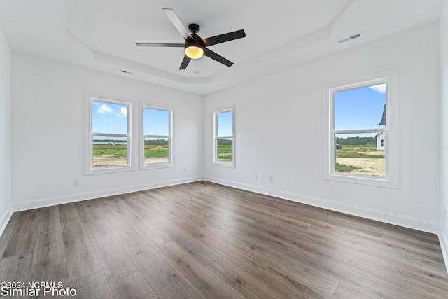 unfurnished room featuring a tray ceiling, ceiling fan, and dark hardwood / wood-style floors