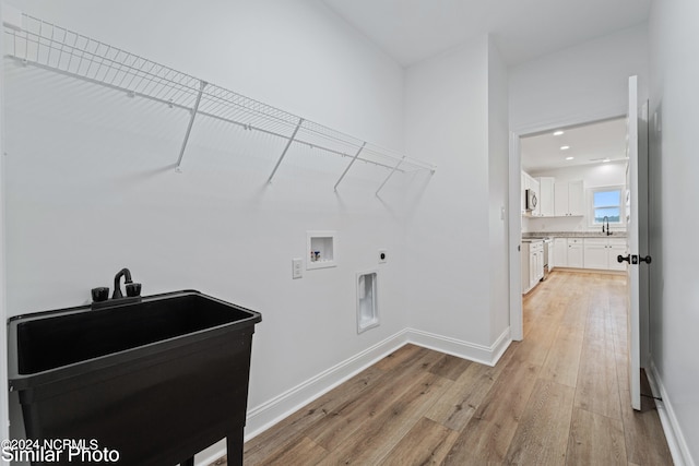 clothes washing area with washer hookup, light hardwood / wood-style flooring, sink, and electric dryer hookup