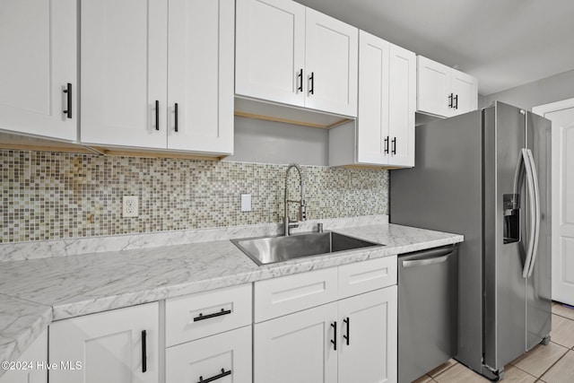 kitchen with tasteful backsplash, light stone counters, stainless steel appliances, sink, and white cabinetry