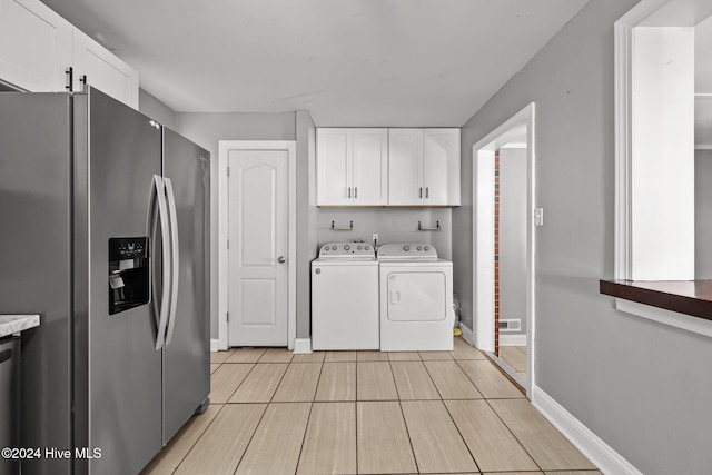 clothes washing area featuring washing machine and clothes dryer, cabinets, and light hardwood / wood-style floors