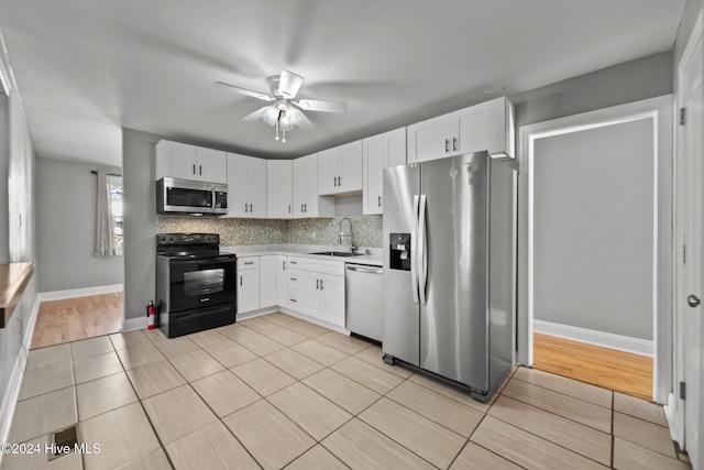 kitchen featuring appliances with stainless steel finishes, tasteful backsplash, sink, light hardwood / wood-style floors, and white cabinetry