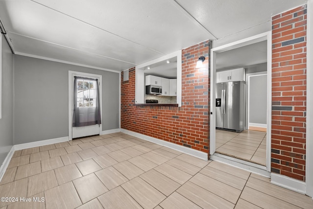 interior space featuring crown molding and brick wall