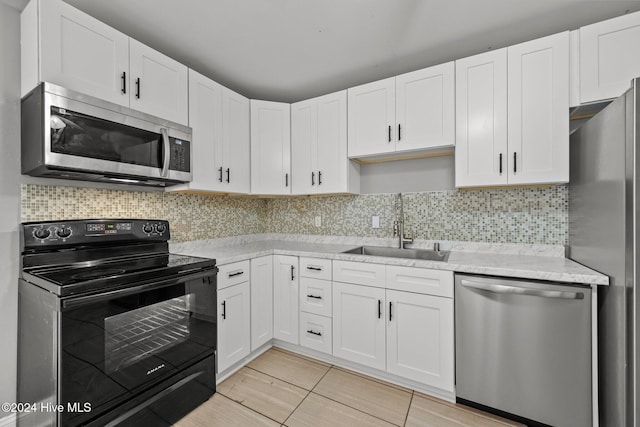 kitchen featuring backsplash, stainless steel appliances, white cabinetry, and sink