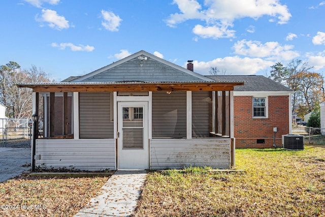 view of front of property featuring a sunroom, central air condition unit, and a front yard