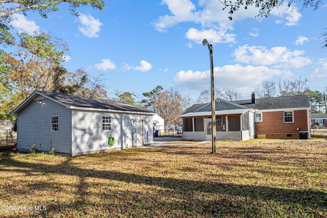 back of house with central AC unit and a yard