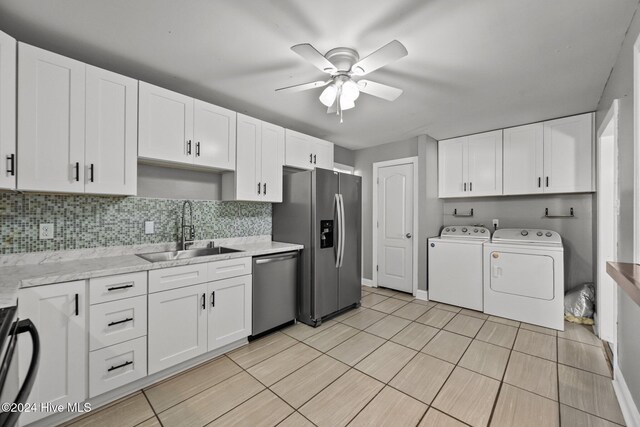 kitchen with white cabinetry, sink, ceiling fan, washing machine and dryer, and appliances with stainless steel finishes