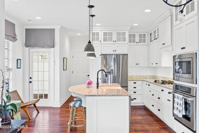 kitchen with a kitchen island with sink, light stone countertops, white cabinets, and appliances with stainless steel finishes