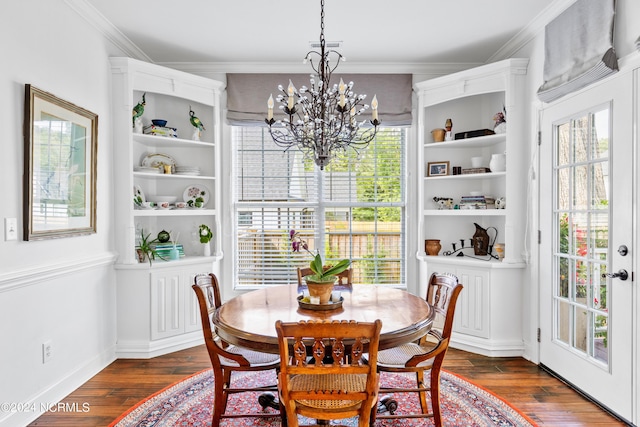 dining space with dark hardwood / wood-style flooring, ornamental molding, and an inviting chandelier