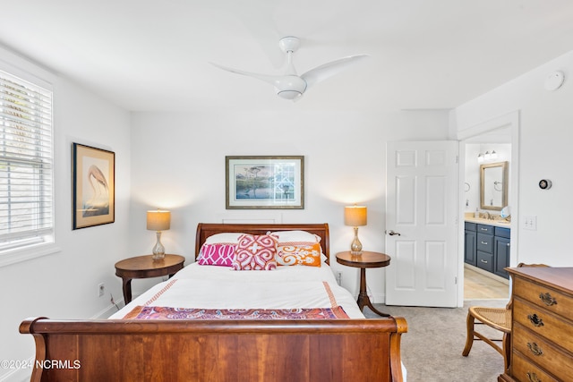 bedroom with sink, light colored carpet, ceiling fan, and ensuite bath