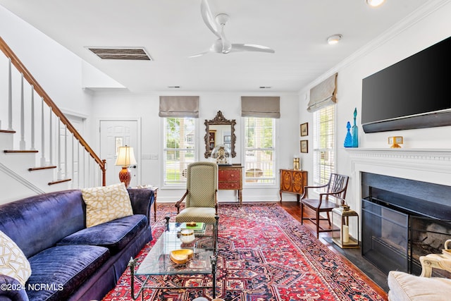 living room with crown molding, dark wood-type flooring, and ceiling fan