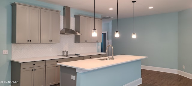 kitchen with pendant lighting, sink, gray cabinetry, a center island with sink, and wall chimney exhaust hood