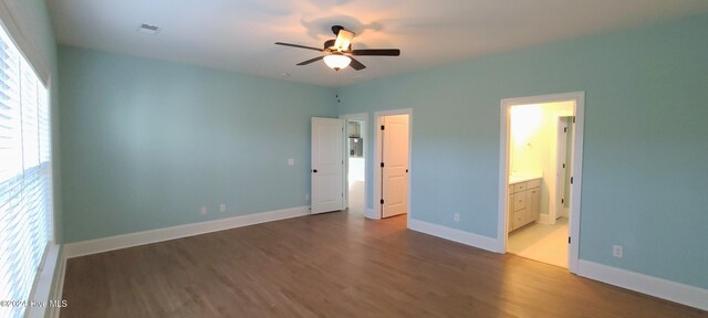 unfurnished bedroom with dark hardwood / wood-style floors, ceiling fan, and connected bathroom