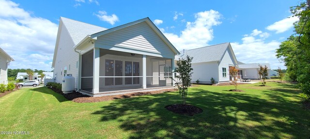 back of property featuring a sunroom and a lawn