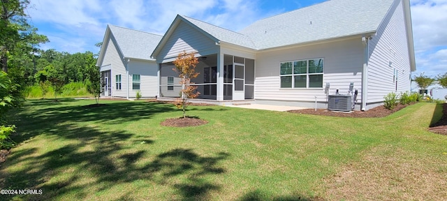 rear view of house featuring central AC, a patio, a sunroom, and a lawn